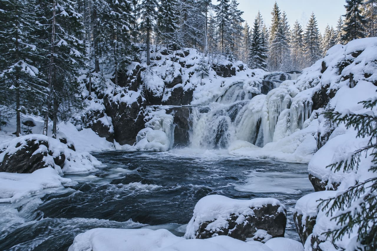 Лесной водопад среди заснеженных валунов и елей
